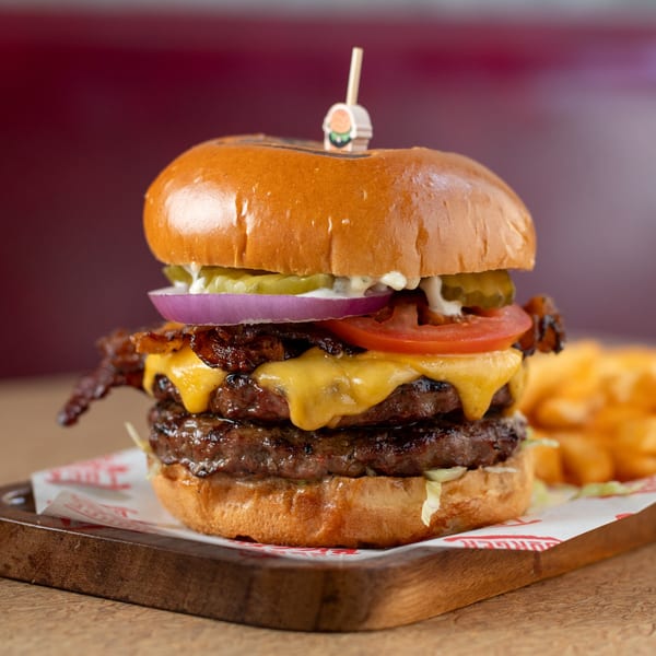 A double Bigger Burger with bacon, cheese, tomato, onion, and pickles, served with fries.