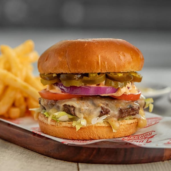 A Bigger Burger with melted cheese, jalapeños, onions, tomato, and lettuce, served with fries.