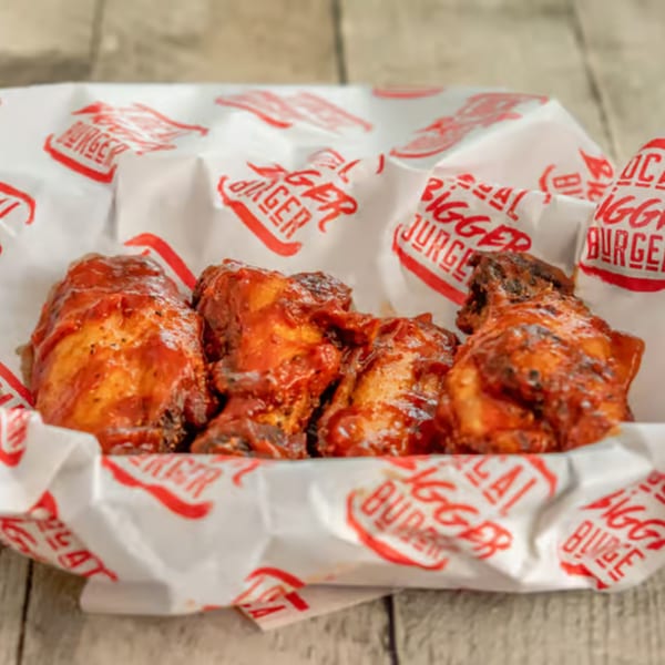 Four barbecue chicken wings in a paper-lined basket from Local Bigger Burger.