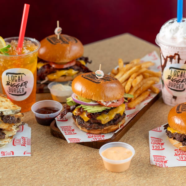 A Local Bigger Burger spread with burgers, fries, quesadillas, a milkshake, and a cold drink.